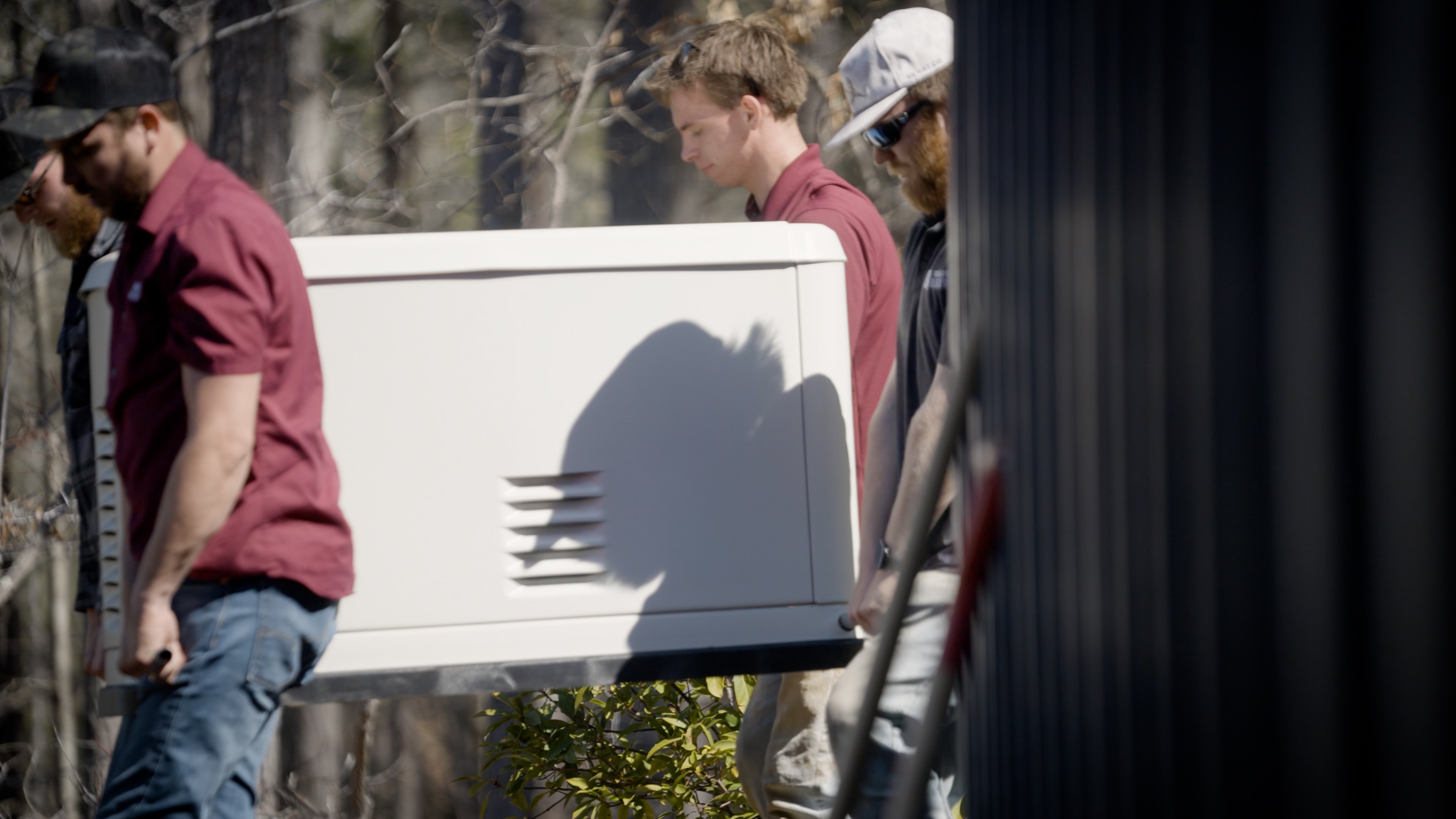 Crew carrying a residential standby generator for a Prosperity project